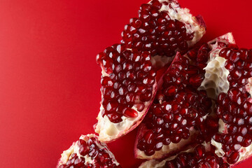 Ruby ripe fresh juicy sliced pomegranate isolated on red background