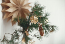 Stylish Christmas Straw Ornaments And Paper Angel On Pine Branches Against Sweden Star. Eco Decor