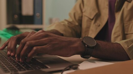 Wall Mural - tilting-up medium close-up with slowmo of serious african-american programmer typing on laptop sitti