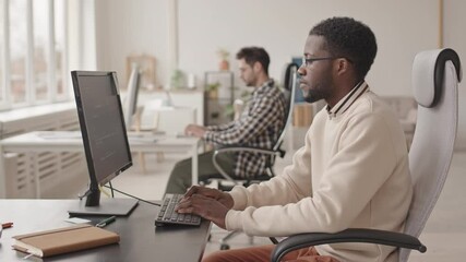 Wall Mural - stab side-view medium shot of young african-american it specialist developing software on pc compute