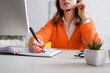 © LIGHTFIELD STUDIOS - cropped view of blurred woman in headset writing in notebook while working at home