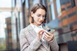 © splitov27 - Young modern business woman using smartphone on the background of business building