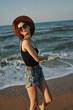 © VICHIZH - cheerful woman in sunglasses and a hat walks along the ocean