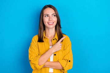 Wall Mural - Photo of positive happy dreamy young woman look empty space point way ad isolated on blue color background
