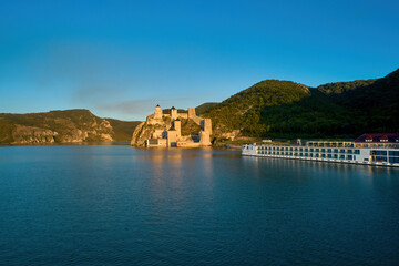 Wall Mural - The medieval fortress of Golubac against iron gate of national park Djerdap, mirroring in the waters of the Danube. Colorful sunset light, blue sky. Aerial shot. Famous tourist place, Serbia.