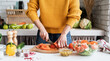 Front view of female hands making salad cutting tomatoes in the kitchen