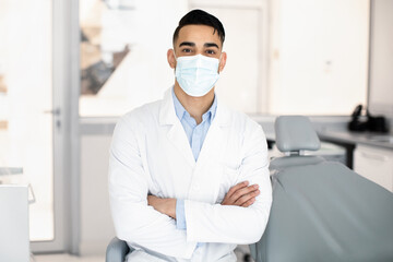 Wall Mural - Dental Services. Portrait Of Handsome Arab Dentist In Uniform And Medical Mask