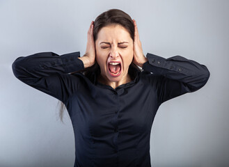 Angry young business woman strong screaming with wild.opened mouth and holding the head the hands in blue shirt on blue background. Closeup.