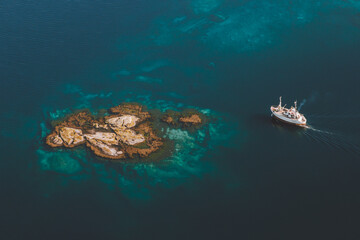 Wall Mural - Island in blue sea and ship sailing aerial view drone scenery from above minimal style
