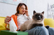 © LIGHTFIELD STUDIOS - selective focus of cat near blurred allergic woman sneezing and taking paper napkin from pack