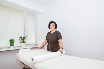 Portrait of a woman masseuse who stands near a massage table