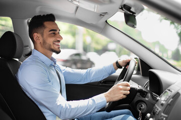 Wall Mural - Joyful arabic guy driving nice auto, side view