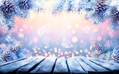 Wall Mural - winter christmas table with fir branches with snow and abstract defocused lights