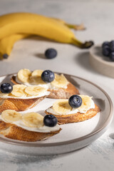 Wall Mural - Healthy breakfast concept, banana sandwiches with blueberry on round plate on the table