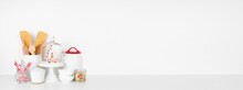 Christmas Theme Kitchenware And Sweets On A White Shelf Or Counter. Banner Against A White Wall Background With Copy Space.