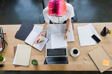 Wall Mural - top view of businesswoman with pink hair holding pen near documents and gadgets on desk.