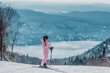 © Maridav - Phone on ski vacation - Woman skier using phone app on ski trail slope in amazing winter nature landscape. Girl looking at mobile smartphone wearing awesome ski clothing, helmet and goggles