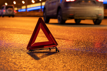 emergency stop sign at night, car breakdown, car stopping on the edge of the road at night, selective focusing, image tinting, illumination and glare in the camera from the lights