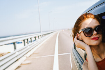 Wall Mural - cheerful woman peeking out of the car window trip adventure lifestyle