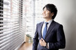 © mapo - 窓辺に立つアジア人のビジネスマン