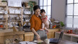 busy asian career mom holding baby is gripping the toast from white plate in wooden style kitchen in the morning.