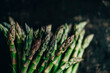 Fresh asparagus on rustic black kitchen table from above. Superfood cooking recipe. Organic green vegetable on vintage board. Growing bio food produce.