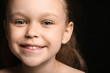 Portrait of pretty smiling little girl on black background