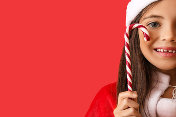 Poster - Cute little girl in Santa hat and with candy cane on color background