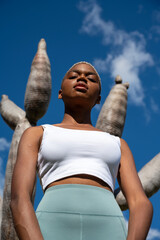confident african american female athlete in activewear and with short hair standing against dragon 