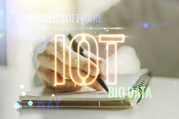 Creative IOT concept with man hand writing in notebook on background. Multiexposure