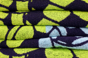 Stack of green black terry towels. Soft background, bath textile with pattern close up