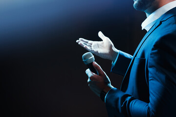 Wall Mural - Motivational speaker with microphone performing on stage, closeup. Space for text
