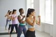 © Studio Romantic - Multiethnic group of confident beautiful young ladies doing active sports workout at fitness studio. Team of strong multiracial women doing fighting move during physical training session at modern gym