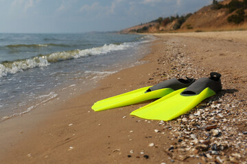 Pair of yellow flippers on sand near sea. Space for text