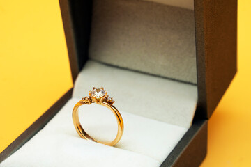 Diamond ring in jewelry gift box on yellow background	