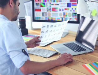 Poster - Portrait of young designer sitting at graphic studio in front of laptop and computer while working online.
