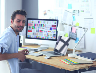 Poster - Portrait of young designer sitting at graphic studio in front of laptop and computer while working online.