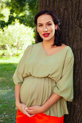 Wall Mural - young pretty brunette pregnant woman outdoor in green park happy smiling, lifestyle people concept