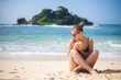 © pridneprovskiy - Happy white Caucasian girl on the beach with a coconut in her hands on the background of the ocean and islands