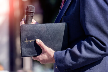 Pastor with a Bible in his hand during a sermon. The preacher delivers a speech