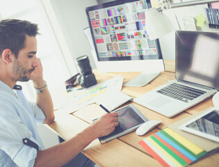 Poster - Portrait of young designer sitting at graphic studio in front of laptop and computer while working online.