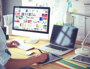Poster - Portrait of young designer sitting at graphic studio in front of laptop and computer while working online.