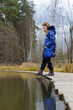 Thoughtful teen caucasian girl standing on footbridge over the lake