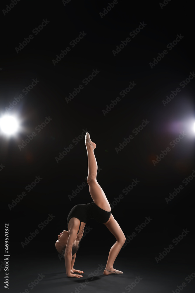 Little girl doing gymnastics on dark background