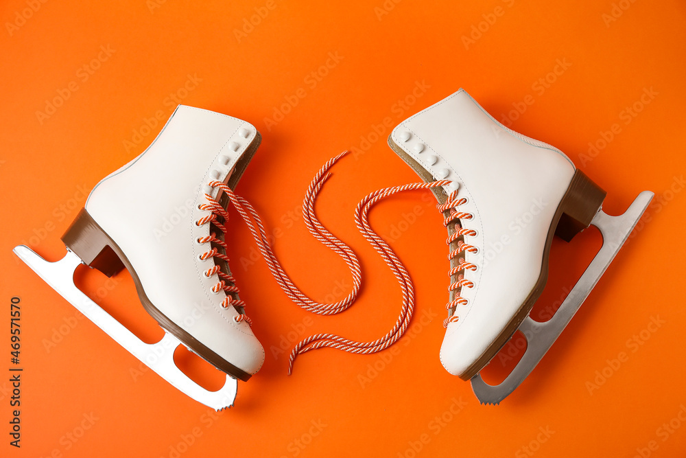 Pair of skates with untied laces on color background