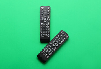 Modern TV remote controllers on green background