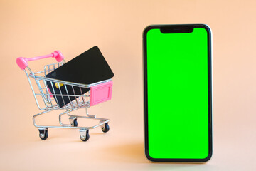 Mobile phone and shopping cart on light yellow background