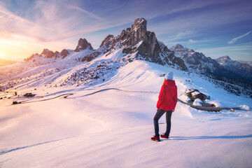 Wall Mural - young woman in snowy mountains at sunset in winter. landscape with beautiful girl on the hill, snow 