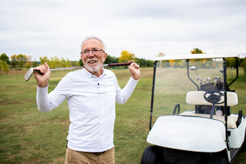 Portrait of an active senior man playing golf at the golf course and enjoying free time outdoors.