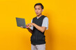 © Bangun Stock Photo - Cheerful handsome young businessman holding laptop and looking at camera on yellow background